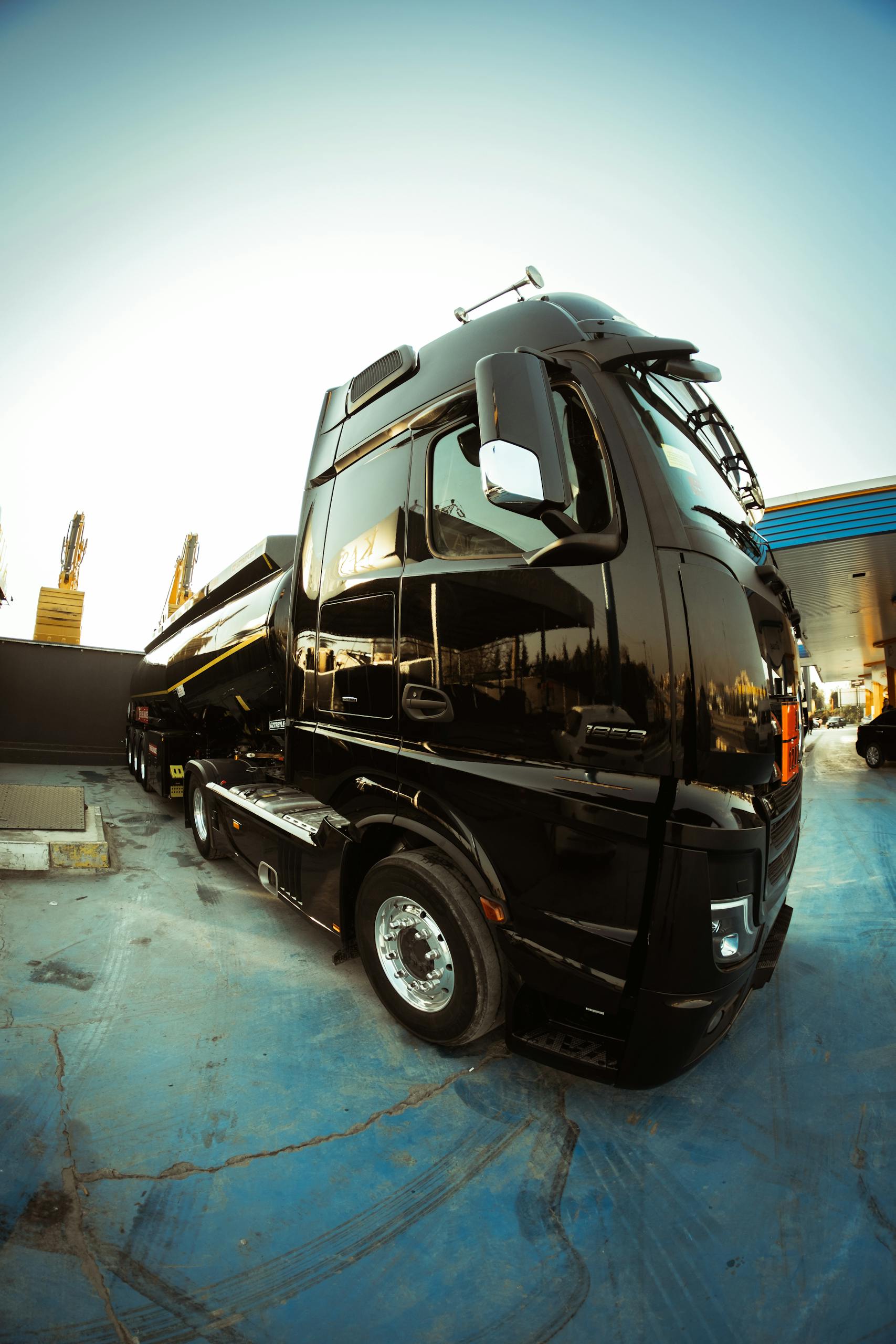 High-angle shot of a sleek black truck parked in an open area under bright sunlight.
