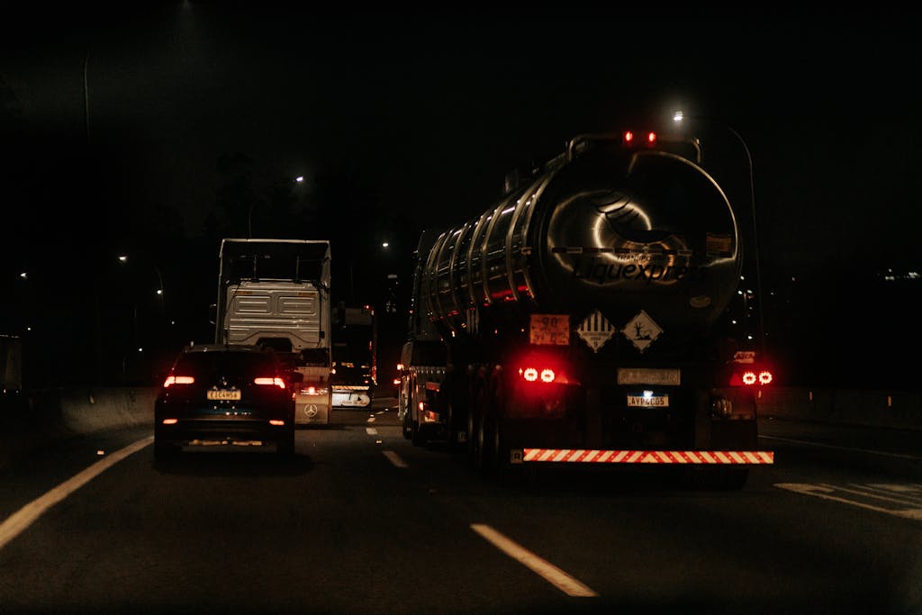 Vehicles drive down a dark highway at night, showcasing traffic and car lights.